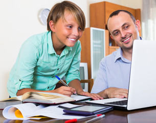 Father helping teenage son with homework.