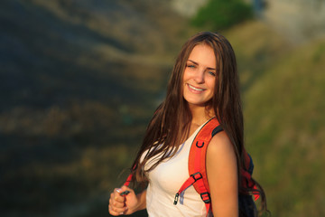 Young woman with red backpack walking on sunset summer.