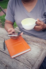 Woman using smart phone with book and pen
