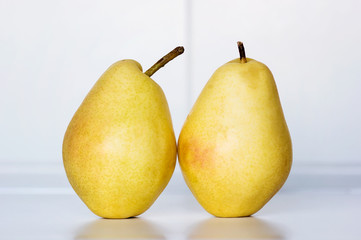 Dos peras amarillas en superficie blanca