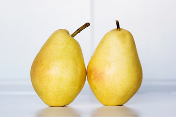 Dos peras amarillas en superficie blanca