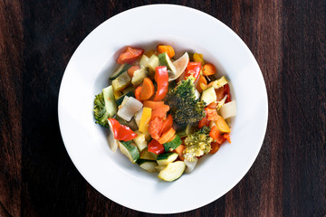 Cooked Roasted Vegetables stewed Tomatoes, Carrots, Peppers, Courgettes, brocoli, onion on plates.
