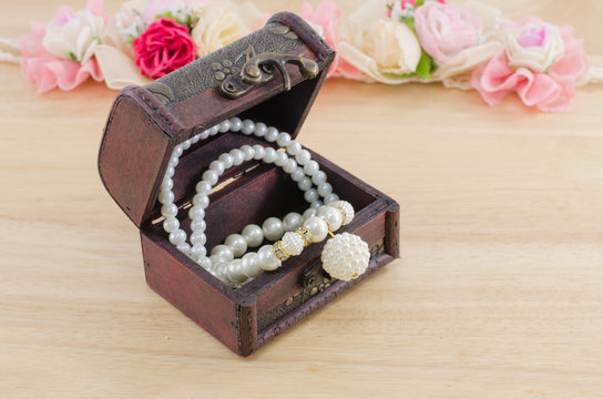 Small wooden chest with white pearl necklace and wooden, flower