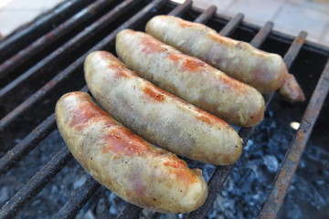 Pork - beef sausages on grill in the summer garden
