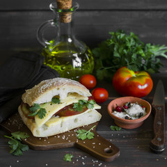 sandwich with tomato and cheese, served on a cutting Board on dark wooden surface. Healthy Breakfast or snack