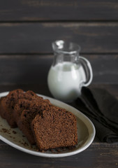 simple chocolate cake on an oval plate on dark brown wooden surface