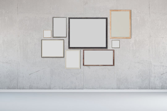 Viele Bilderrahmen an Wand aus Beton