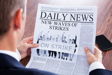Close-up Of Businessman Reading News On Newspaper