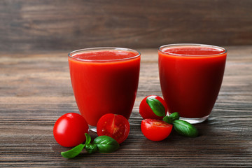 Glasses of tomato juice with vegetables on wooden background