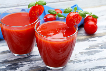 Glasses of tomato juice with vegetables on wooden background