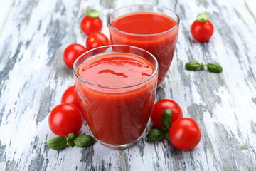 Glasses of tomato juice with vegetables on wooden background