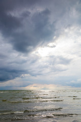 Sea waves on a sandy beach with stormy sky