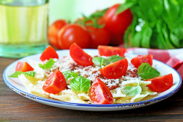 Pasta bolognese with cherry tomatoes in white plate on wooden table, closeup