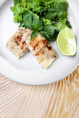 Dish of fish fillet with greens and lime on table close up