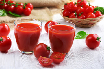 Glasses of tomato juice on wooden table, closeup