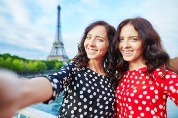 Beautiful twin sisters taking selfie in front of Eiffel Tower