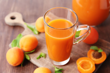 Glass cup of apricot juice and fresh fruits on table close up