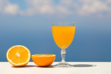 Orange juice and slices of orange on sea view and sky background
