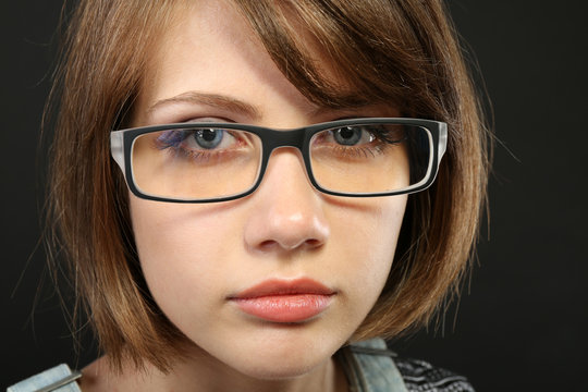 Attractive young woman with glasses on gray background