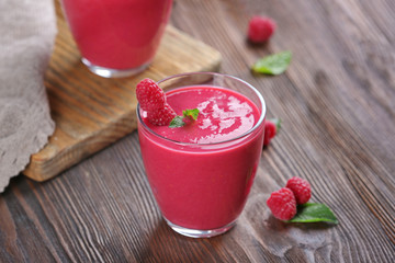 Glasses of raspberry milk shake with berries on wooden table close up