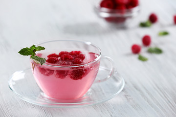 Cup of raspberry drink with berries on wooden table close up