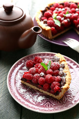 Piece of tart with fresh raspberries, on wooden background