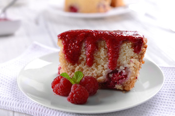 Fresh pie with raspberry jam in white saucer on wooden table, closeup