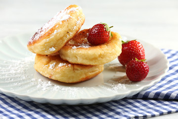 Fritters of cottage cheese with strawberry and sugar in plate on table, closeup