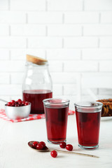 Two glasses with cherry juice on table, on light background