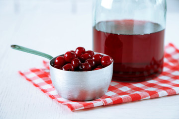 Sweet homemade cherry juice on table, on light background