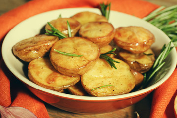 Delicious baked potato with rosemary in bowl on table close up