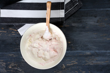 Delicious vanilla ice cream in bowl and frozen berries, on wooden background