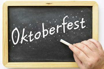 oktoberfest written on blackboard with female hand and chalk