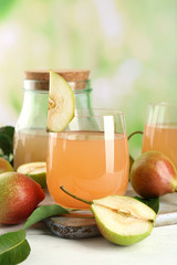 Glass of juice with fresh pears on wooden table on blurred background