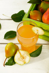 Glass of juice with fresh pears on wooden table, closeup