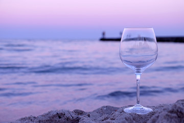Romantic glass of wine sitting on the beach at colorful sunset