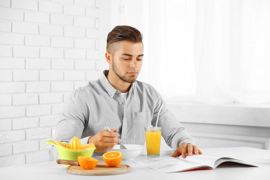 Young man having breakfast with oranges