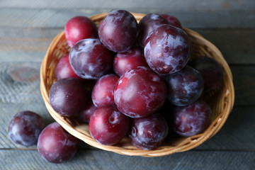 Delicious ripe plums in basket on table close up