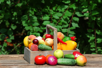 Heap of fresh fruits and vegetables in crate on table outdoors