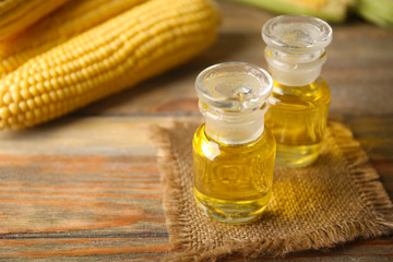Fresh corn with bottles of oil on table close up