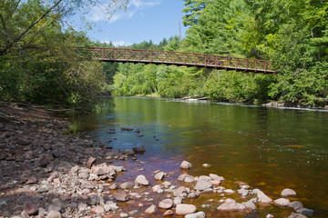 Shallow river flowing under a foot bridge.