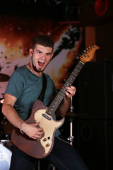 Obraz premium Young man playing on electric guitar at pub