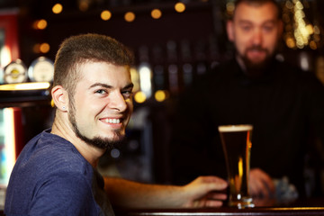 Young man drinking beer in bar