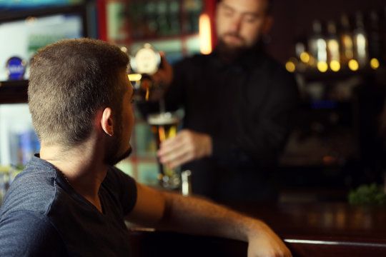 Young man drinking beer in bar