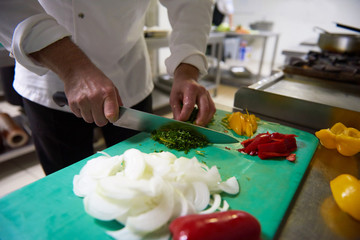 Obraz na płótnie Canvas chef in hotel kitchen slice vegetables with knife