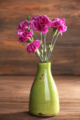 Purple clove in vase on wooden background