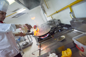 chef in hotel kitchen prepare food with fire