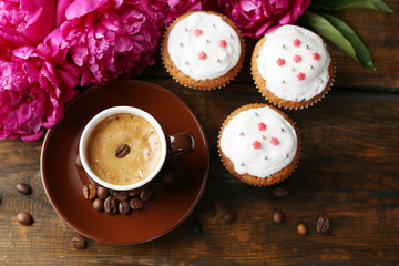 Composition with cup of coffee, muffins and peony flowers on wooden background