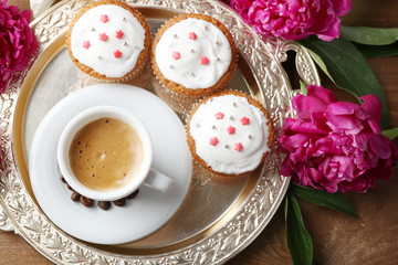 Composition with cup of coffee, muffins and peony flowers on tray, on wooden background