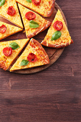 Slices of tasty cheese pizza with basil and cherry tomatoes on table close up